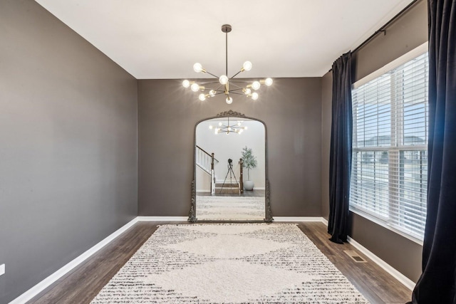 interior space featuring baseboards, a chandelier, and dark wood-type flooring