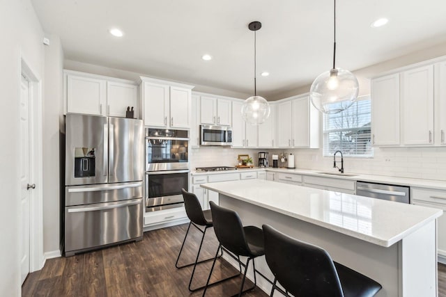 kitchen with decorative backsplash, white cabinetry, stainless steel appliances, and a sink