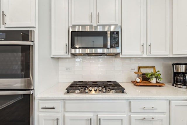 kitchen with appliances with stainless steel finishes, backsplash, and white cabinets