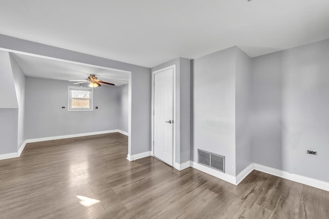 spare room with ceiling fan, wood finished floors, visible vents, and baseboards