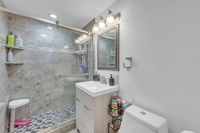 bathroom with toilet, a shower stall, and vanity