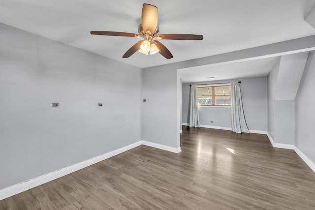 empty room with a ceiling fan, baseboards, and wood finished floors