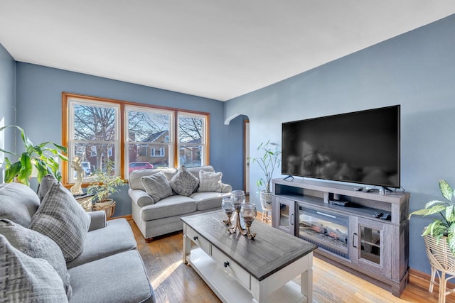 living area featuring arched walkways, baseboards, and hardwood / wood-style flooring