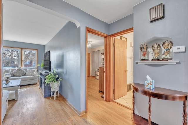 hall featuring light wood-style flooring and baseboards