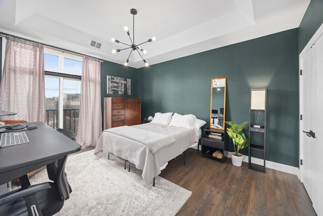 bedroom with wood finished floors, a raised ceiling, visible vents, and baseboards