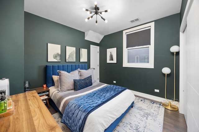 bedroom featuring visible vents, a notable chandelier, baseboards, and wood finished floors