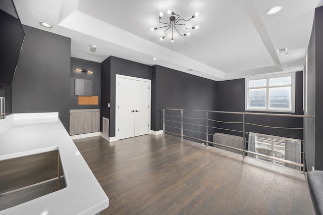 interior space with recessed lighting, a sink, wood finished floors, baseboards, and a tray ceiling