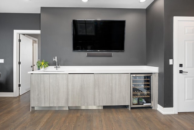 bar with wine cooler, dark wood-style flooring, a sink, and baseboards