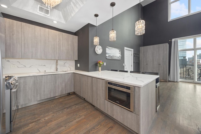 kitchen featuring modern cabinets, a peninsula, stainless steel appliances, light brown cabinets, and a sink