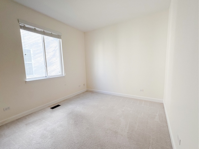 empty room featuring light carpet, visible vents, and baseboards