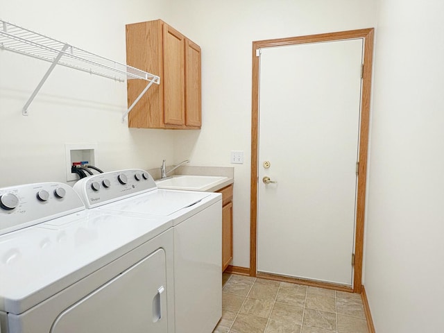 laundry area featuring cabinet space, baseboards, separate washer and dryer, and a sink