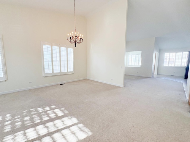 unfurnished room featuring a notable chandelier, a high ceiling, baseboards, and light colored carpet