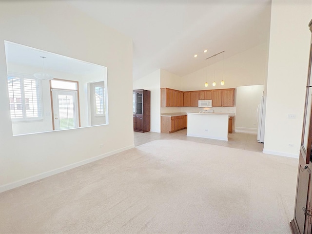 unfurnished living room featuring baseboards, high vaulted ceiling, and light colored carpet