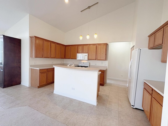 kitchen with light tile patterned floors, white appliances, light countertops, hanging light fixtures, and brown cabinets