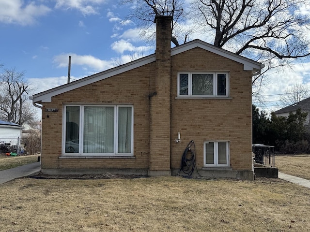 back of property featuring brick siding, a yard, and a chimney