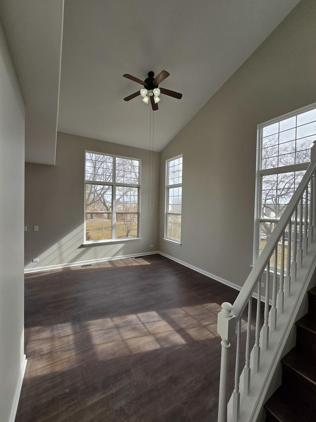 unfurnished living room with vaulted ceiling, ceiling fan, wood finished floors, baseboards, and stairs