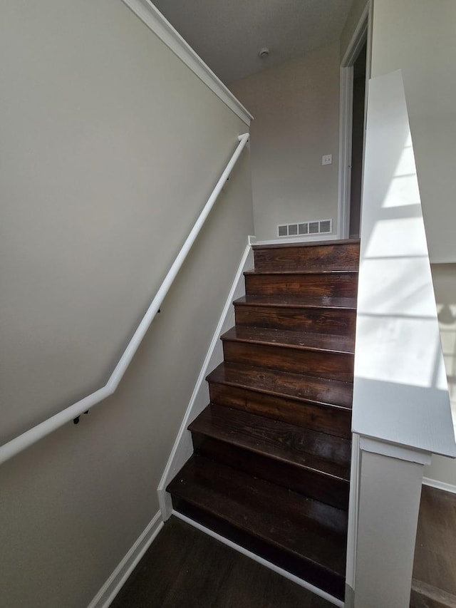 staircase featuring baseboards, visible vents, and wood finished floors