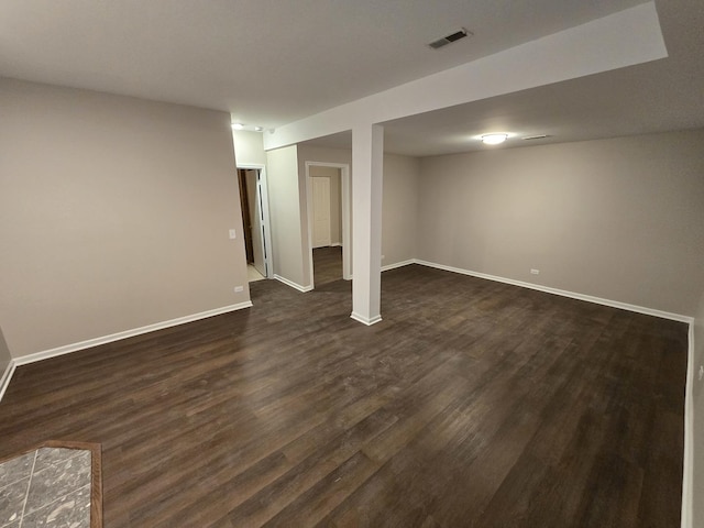 finished below grade area with baseboards, visible vents, and dark wood-type flooring