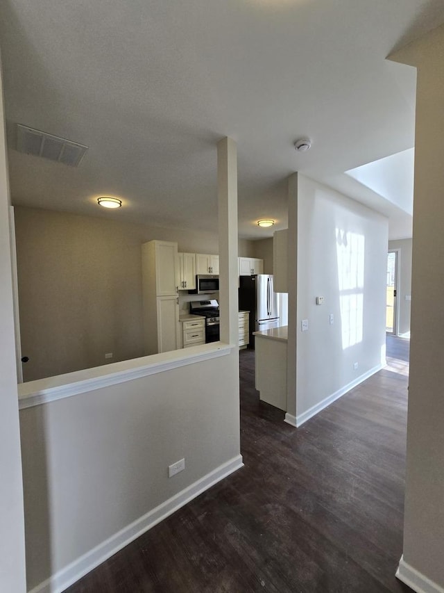 kitchen with visible vents, baseboards, white cabinetry, appliances with stainless steel finishes, and dark wood finished floors