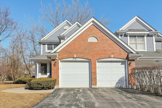 view of front facade with an attached garage, brick siding, driveway, and roof with shingles