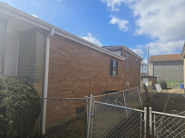 view of property exterior featuring a gate, brick siding, and fence