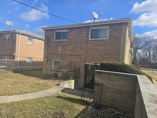 rear view of property featuring a yard, brick siding, and fence