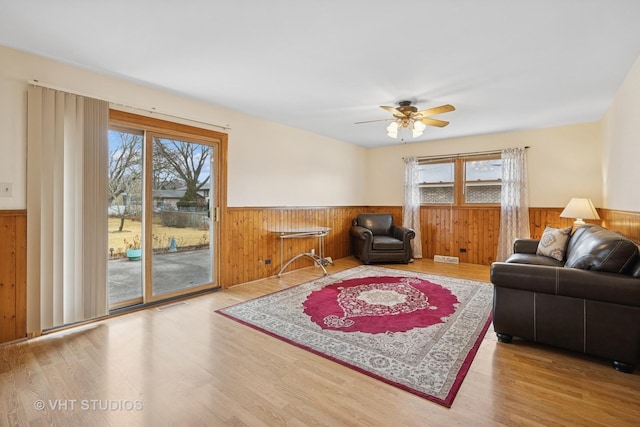 living room with wainscoting, wood finished floors, visible vents, and wooden walls