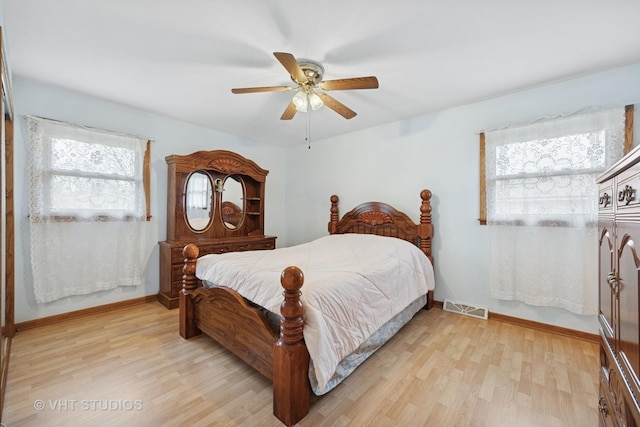 bedroom featuring light wood-style floors, visible vents, baseboards, and a ceiling fan