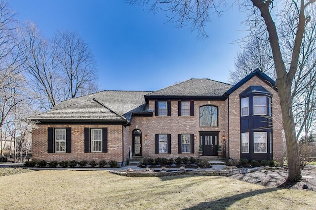 view of front facade with brick siding and a front yard