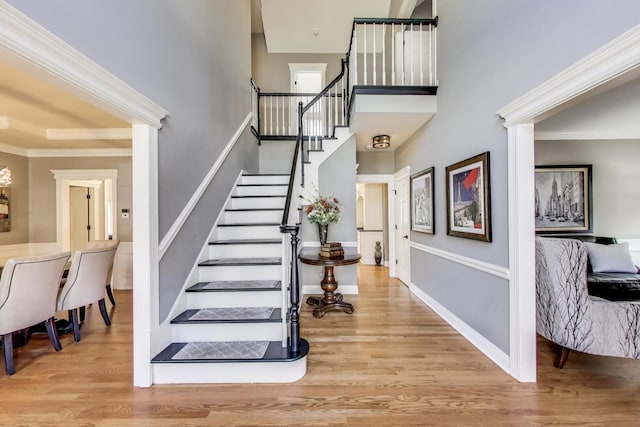 foyer with ornamental molding, stairs, baseboards, and wood finished floors