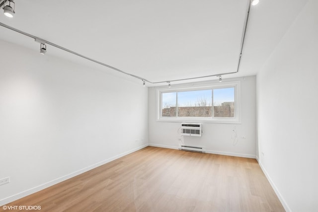 spare room featuring light wood finished floors, a wall mounted AC, and rail lighting