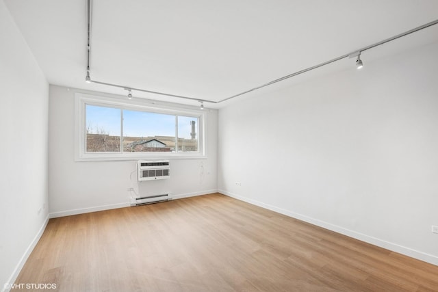 unfurnished room featuring light wood finished floors, baseboards, a baseboard radiator, rail lighting, and a wall mounted AC