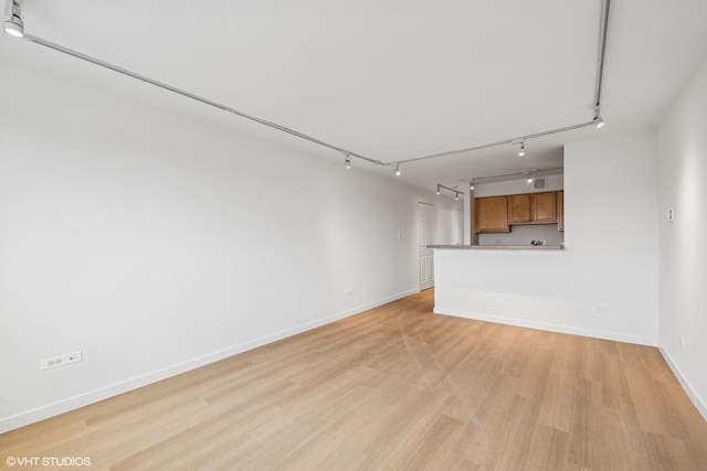 unfurnished living room featuring light wood-type flooring and baseboards