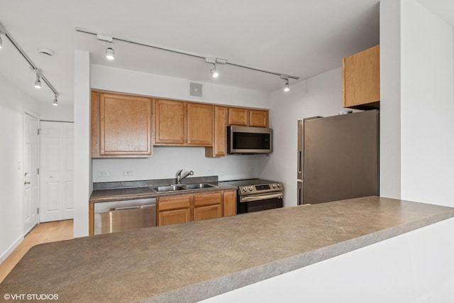 kitchen featuring stainless steel appliances, a sink, visible vents, brown cabinetry, and track lighting