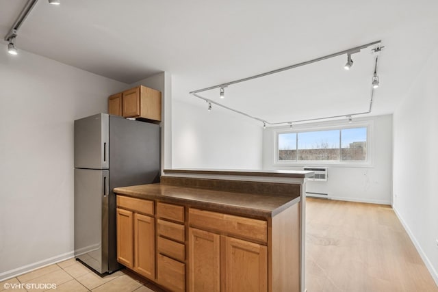 kitchen featuring dark countertops, brown cabinets, a wall mounted air conditioner, freestanding refrigerator, and track lighting