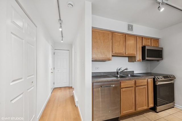 kitchen featuring visible vents, dark countertops, appliances with stainless steel finishes, brown cabinets, and a sink