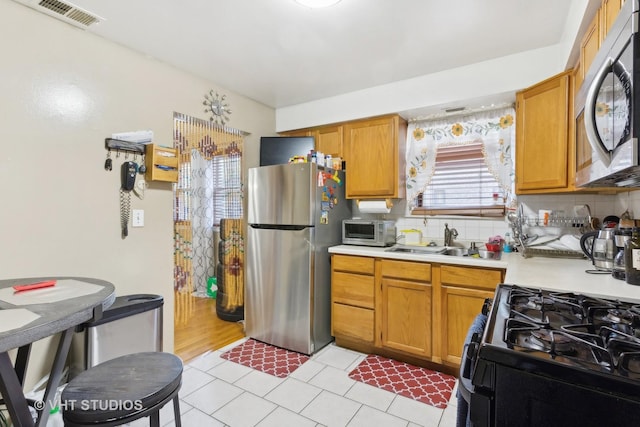 7311 N Ashland Blvd Unit 2A, Chicago, IL 60626 - kitchen featuring appliances with stainless steel finishes, light countertops, backsplash, light tile patterned floors, and brown cabinets