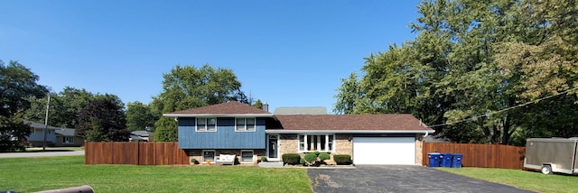 tri-level home with a front lawn, fence, a garage, and driveway