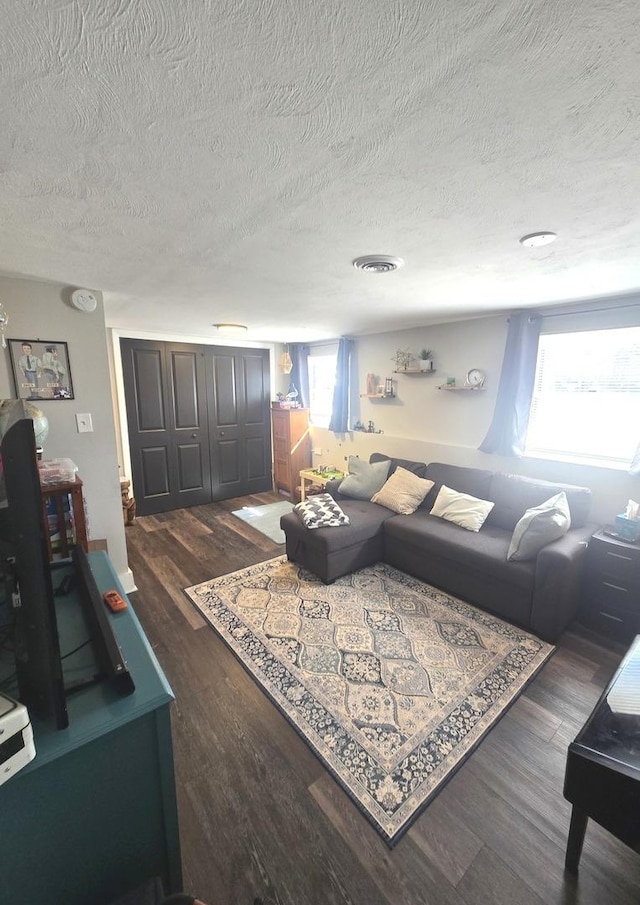 living area featuring wood finished floors, visible vents, and a textured ceiling