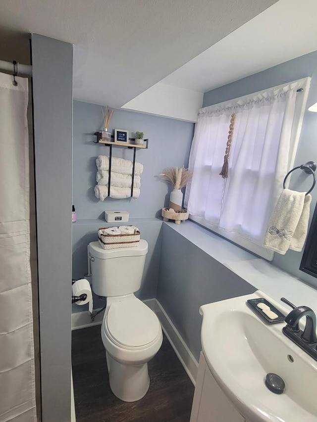 bathroom featuring a sink, baseboards, toilet, and wood finished floors