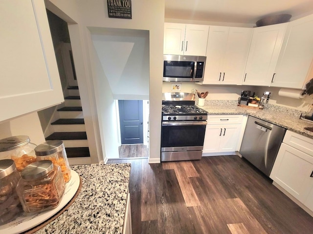 kitchen featuring stainless steel appliances, light stone countertops, dark wood-style floors, and white cabinetry