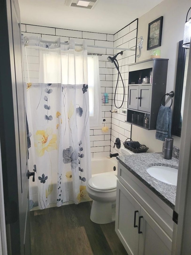 bathroom featuring visible vents, shower / tub combo with curtain, toilet, wood finished floors, and vanity