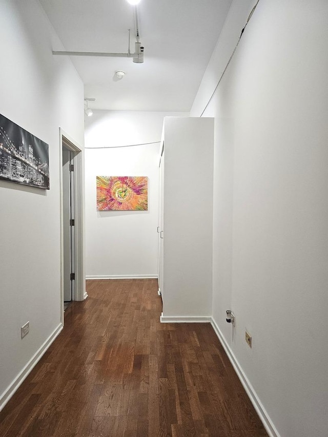 corridor with baseboards and wood finished floors