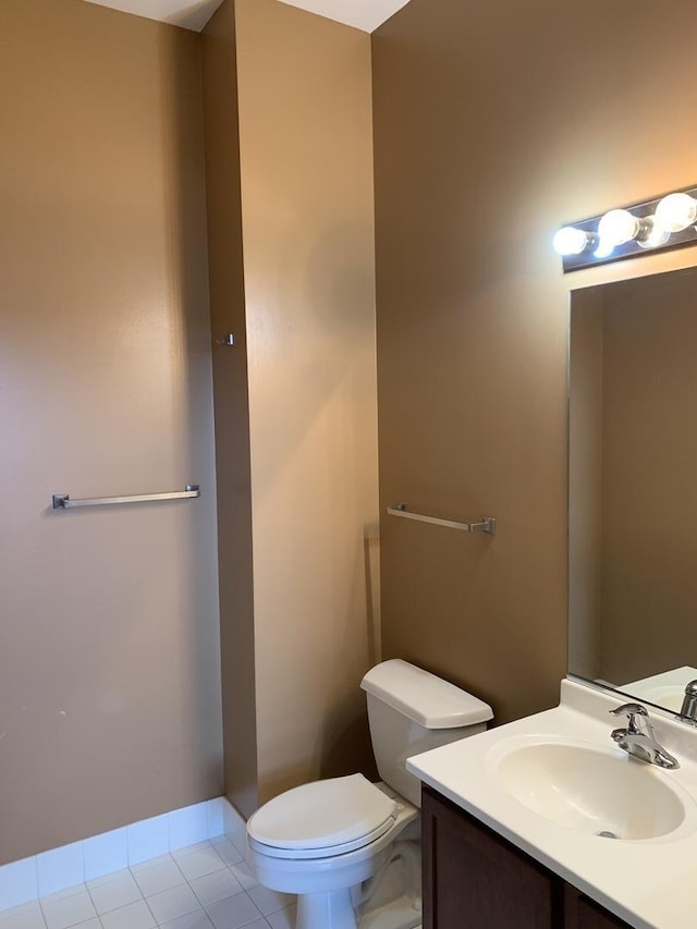 half bathroom featuring tile patterned flooring, baseboards, vanity, and toilet