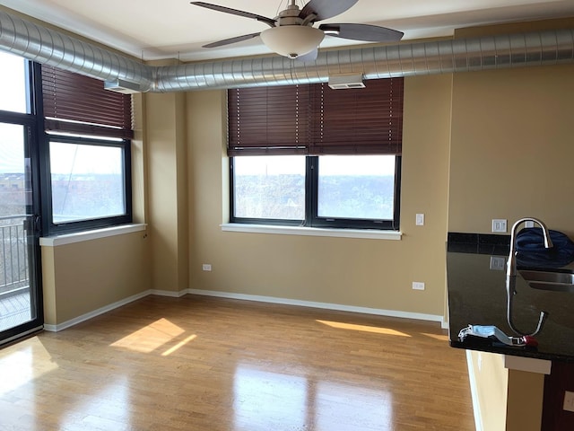 empty room with a wealth of natural light, a sink, and light wood-style flooring