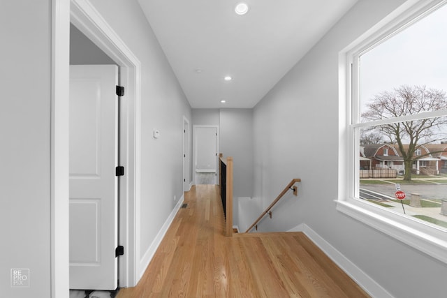 corridor featuring plenty of natural light, baseboards, and an upstairs landing