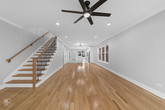 unfurnished living room featuring baseboards, stairway, crown molding, light wood-type flooring, and recessed lighting