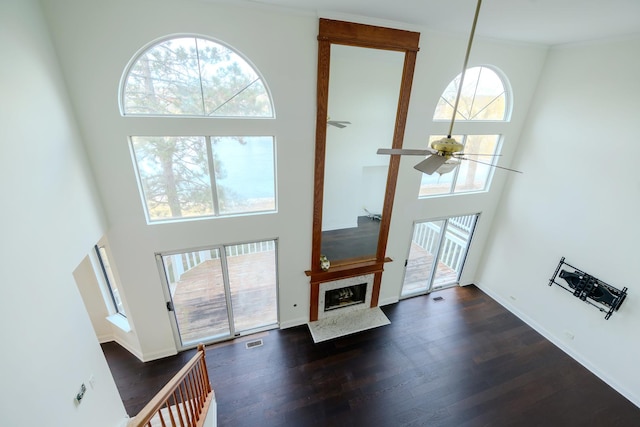 living area featuring a high ceiling, a fireplace, wood finished floors, and baseboards