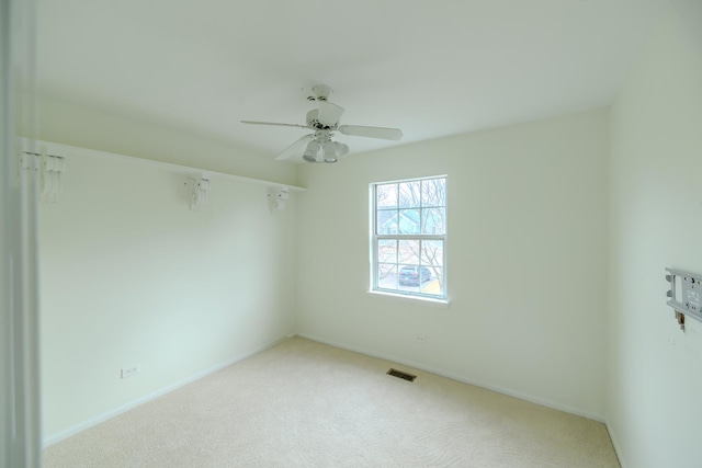 carpeted empty room with baseboards, visible vents, and a ceiling fan