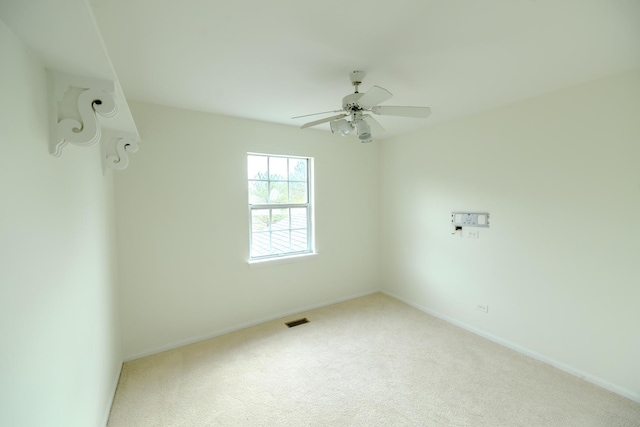 empty room with a ceiling fan, carpet flooring, visible vents, and baseboards